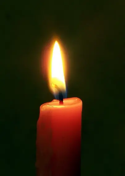 Close up of a single lit candle in a dark room