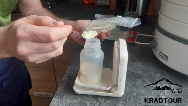 Abwiegen des Milchpulvers für 500ml Milch in eine kleine Plastikflasche.