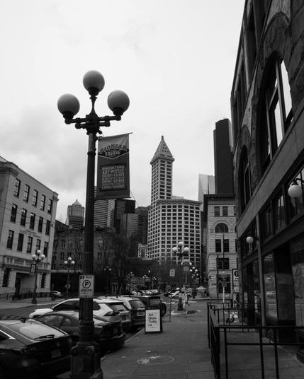 A black and white photo of buildings in downtown Seattle. In the center of the shot stands Smith Tower.