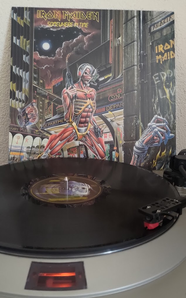 Iron Maiden's "Somewhere in Time" playing on a Denon DP-30L turntable.

In the background, the album cover is visible. It depicts the band's mascot Eddie as a futuristic Cyborg in front of a Cyberpunk-esque cityscape.