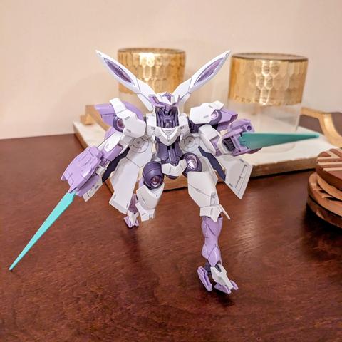 A white and lavender Gundam with two green swords is posed in a lunging stance