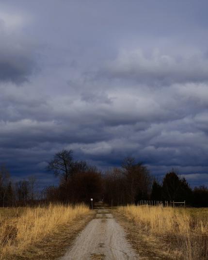Stormy dark sky above a yellow barren field.