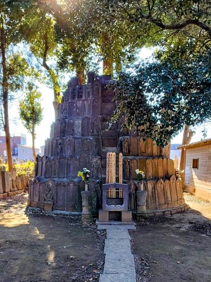 A cone-shaped stone structure with the top half intentionally missing. It's tiered and lined with similar sized relief stones, not dissimilar to western gravestones. There are seven levels of this, all in all about I'm out 24ft tall. If I understand it correctly, these towers or mounts house the remains or the memory of those whose graves cannot be attended to by their descendants. The sun is blocked mostly by the trees that shade the structure.