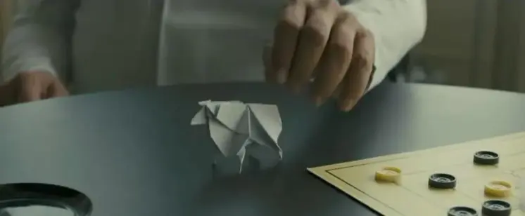An origami sheep being placed on a table.