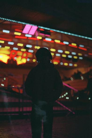Backlit photo with a silhouette in front of a ride with bright lights