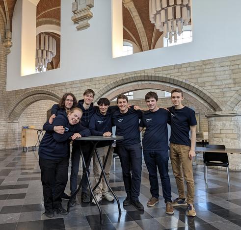 A group of ULYSSIS members is smiling in a group formation after setting up tables for the Open Source Job Fair
