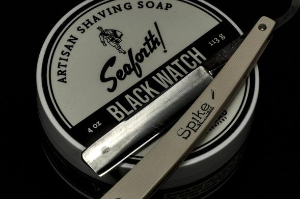 A desaturated picture of a Union Cutlery Spike straight razor on a tub of Spearhead! Black Watch soap.