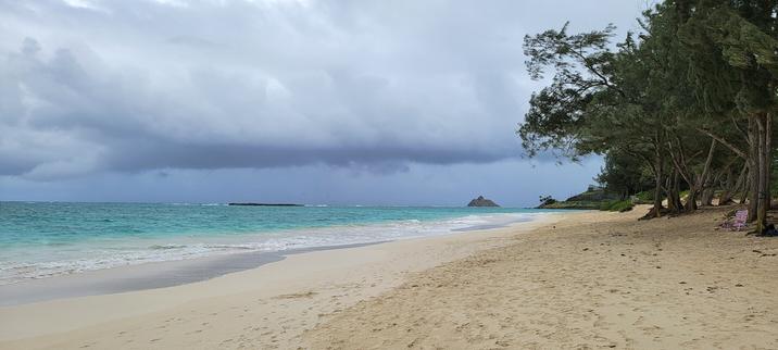 Long neach with white sand and one pointy island and one flat island