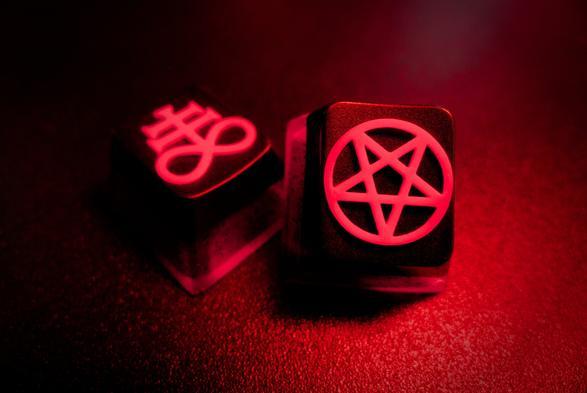 photograph of two artisan keycaps, one with the Brimstone symbol and the other with an inverted Pentagram
