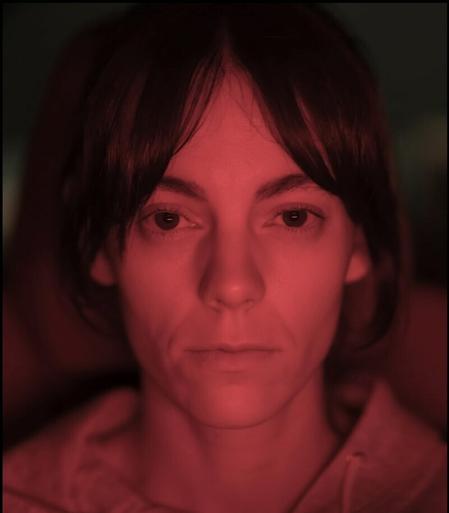 series star Vicky Luengo makes eye contact in a close up. The images is tinted red. She looks very serious.