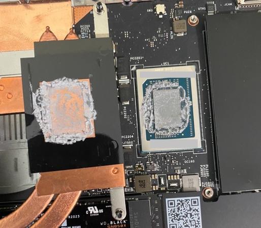 cpu on laptop motherboard with heatsink resting next to it, both with stock thermal paste