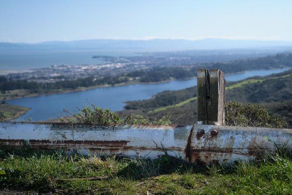 Old railings in front of a lake and some mountains. Sweeping views.