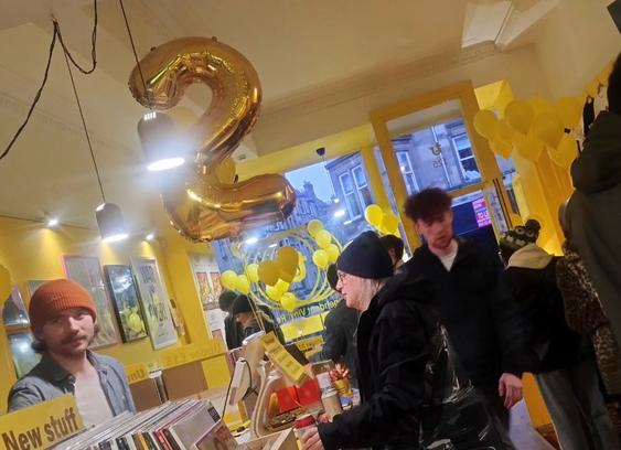 Jake behind the till at Thorne Records as they had a second birthday party, a large, gold foil number two balloon floating above the desk