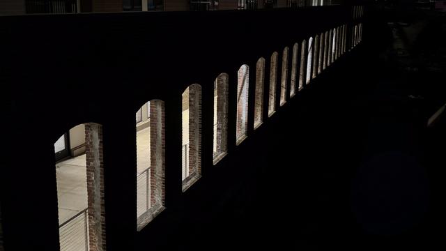 A row of backlit window-shaped holes in a brick wall at night