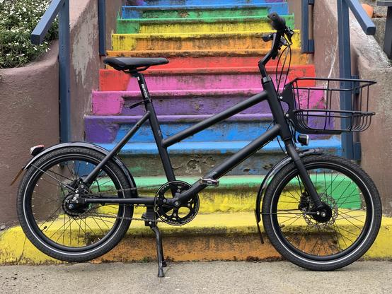 A black bike in front of stairs with rainbow-colored steps.