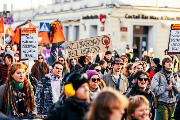 Tłum na manifie, transparenty m. in.:

PRECZ Z PATRIARCHATEM
PRECZ Z KAPITALIZMEM

oraz 

Dość zwlekania
DOSTĘPNA ABORCJA TERAZ
