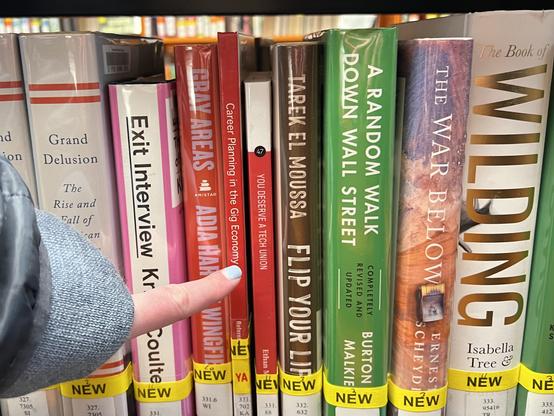 A library shelf of newly-acquired nonfiction books, with my latest book YOU DESERVE A TECH UNION in the middle. A person’s finger is pointing at my book from off-camera.
