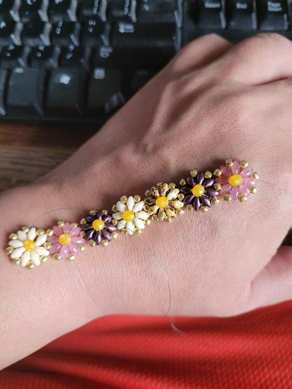 A string of seven linked beaded flowers made of Superduo beads with yellow 3x4mm rondelle beads acting as flower centers.