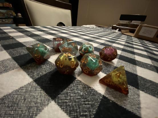 A collection of colorful polyhedral dice on a checkered tablecloth.