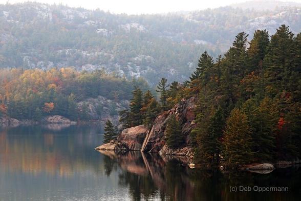 Misty La Cloche Mountain range George Lake Ontario with reflections on the lake and colorful foliage and rocky pine laden shores