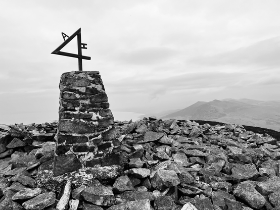 Rocky Mountain top with an iron ‘4’ on a cairn. Black and white photo.