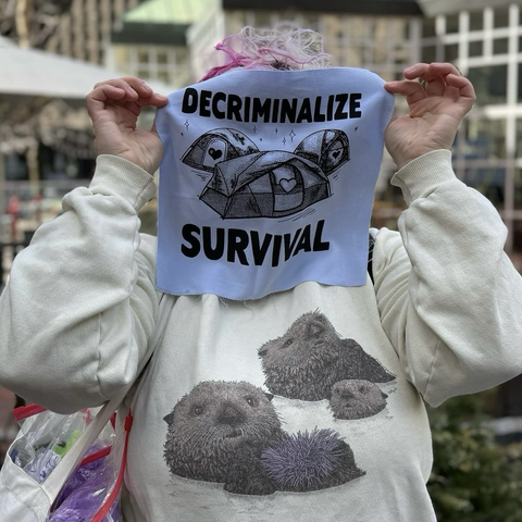 One of our volunteers holding up a decriminalize survival patch.