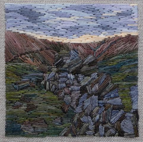 Stitched artwork depicting a dark moorland hillside with a tumble down dry stone wall leading away from the eye. The sun has just set and there is a bright line of sunshine on the horizon beneath grey/purple clouds