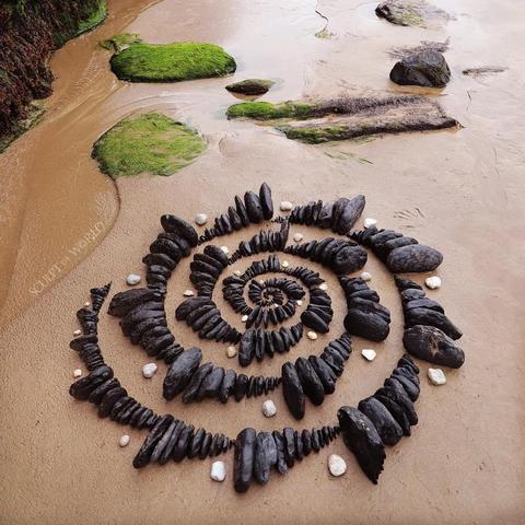 Rocks collected from the seashore, arranged in a spiral, but the spiral has layers of larger to smaller rocks. The effect is mesmerising.