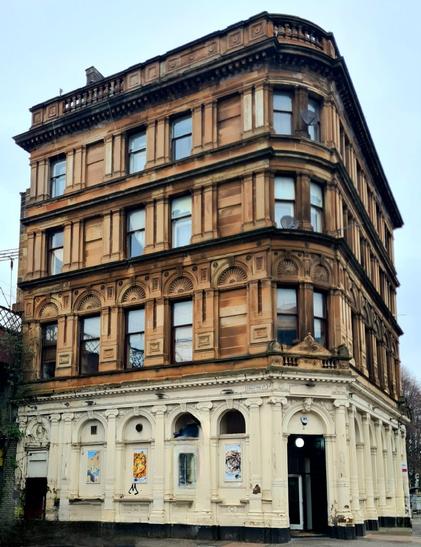 A four- storey corner tenement building with a business premises on the ground floor.