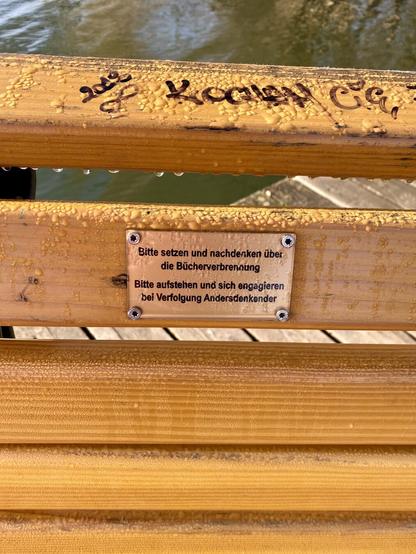 The bench has a little sign that says: “Bitte setzen und nachdenken über die Bücherverbrennung 
Bitte aufstehen und sich engagieren bei Verfolgung Andersdenkender”
Roughly: Please sit and reflect on the book burnings.
Please get up and do something when people who think differently get persecuted.