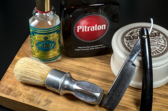 A ceramic container of The Fat propping up a Fine India Steel W&B straight razor next to a unbleached Rubberset 400 boar brush, a bottle of Pitralon splash, and a bottle of Kölnisch Wasser