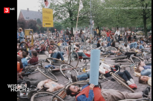 70er Jahre, große Straße, viele Fahrräder und Menschen liegen auf der Straße