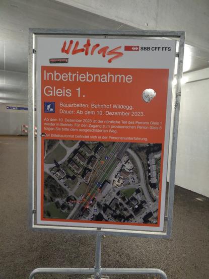 SBB-Infotafel zu einer Gleisänderung. Oben auf der Tafel ist "Ultras" draufgesprayt und ein Kleber draufgeklebt. Die Tafel ist temporär und ist auf einem Beton-Block angebracht.
