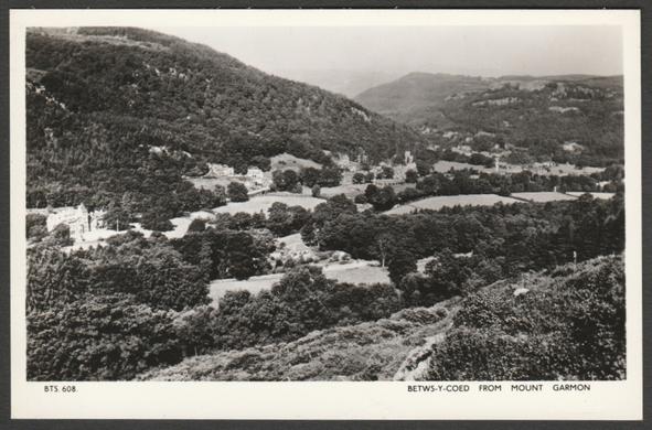 Monochrome real photographic postcard showing a view of Betws-y-Coed as seen from Mount Garmon in Caernarvonshire in Wales.
Published by Marimex Ltd, Colwyn Bay, No BTS. 608, c.1950s.
Postally unused.
Very good condition, with very slight corner bumps.