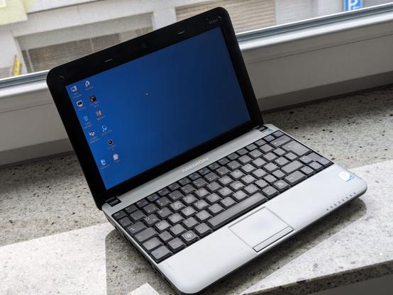 Ein Netbook (Medion E1212 von 2009) steht aufgeklappt und eingeschaltet auf einer Fensterbank.
