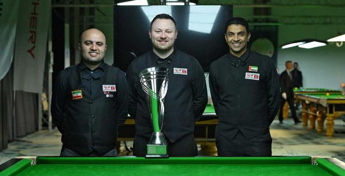 Sarkhosh, Jones und Shehab posieren mit breitem lächeln und einer großen Trophäe hinter der Bande des Snookertisches.