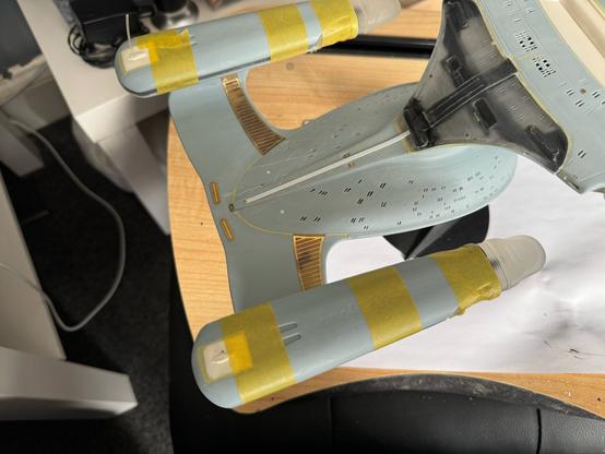 View of both warp nacelles with 3 strips of yellow masking tape at the front, middle and back of each to hold all the parts in place.