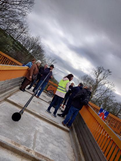 Alphornbläser auf der Brücke, umgeben von einer Gruppe Menschen