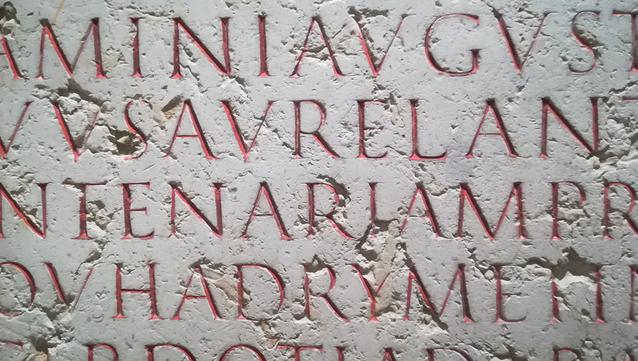 Photograph of a lapidary engraving, red painted letters on white stone.