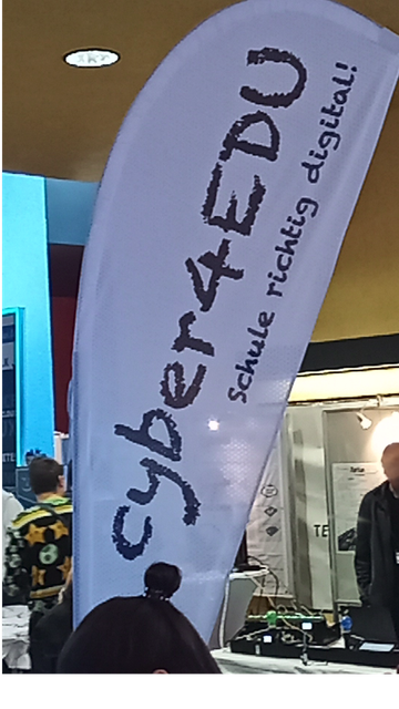 weiße Beachflag mit schwarzem Schriftzug "cyber4EDU. Schule richtig digital!" von cyber4EDU am Stand bei den CLT2024