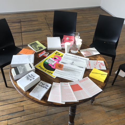 Une table ronde en bois sur laquelle nos livres et affiches sont disposés