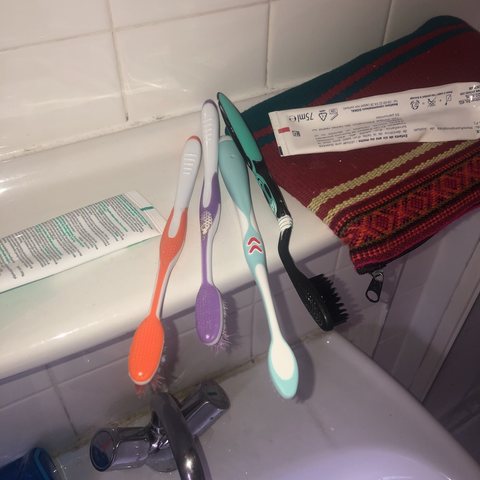 Quatre brosses à dent colorés sur une étagère de salle de bain