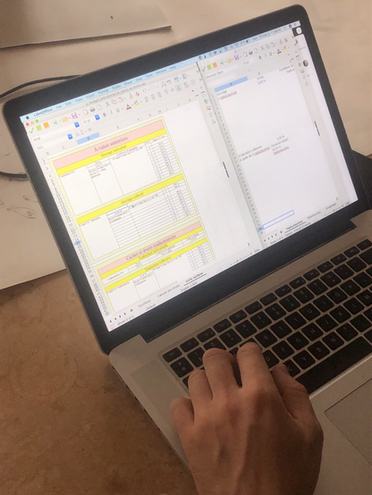 Un ordinateur avec la main d’une personne en train de taper sur le clavier, sur l’écran allumé un tableur excel avec des chiffres