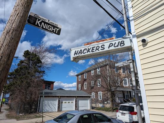 A picture of a simple sign sticking out from a building that says "hacker's pub"