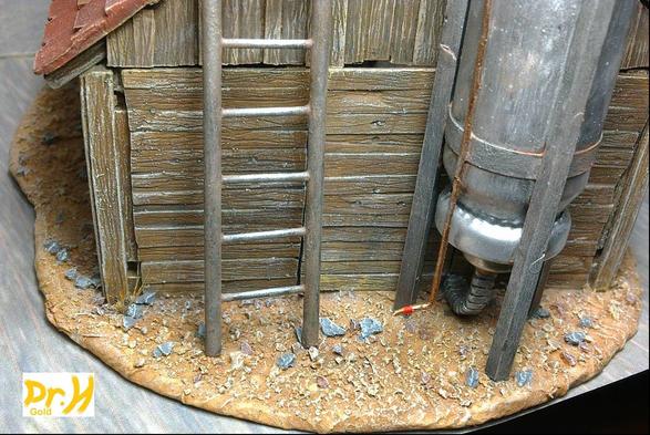 View of the outside of the hut kit example build, showing a ladder and scratch-built storage tank against the wall of the hut.