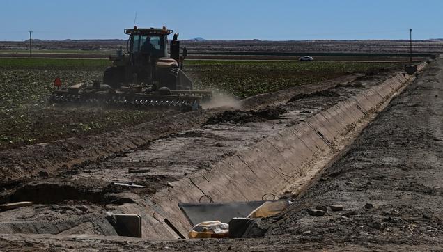 photo - framer prepares field next to dry irrigation canal
