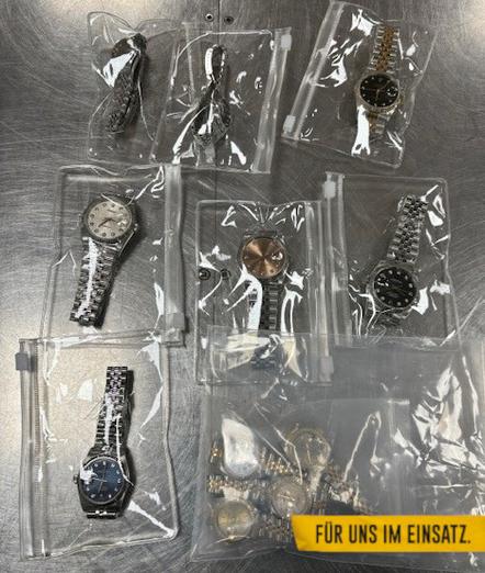 Auf einem Stahltisch liegen die gefundenen Uhren. Die Uhren sind in durchsichtige Plastiktüten vergepackt.