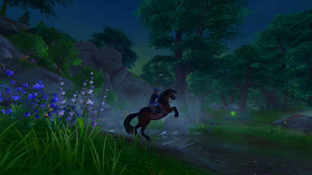 A screenshot from the video game Star Stable. A girl on a rearing horse at the edge of a misty stream in the Hollow Woods in the very early morning darkness. Flowers and grass in the foreground on the left side of the image in front of a rocky hillside. Trees and fireflies in the background on the right side of the image.