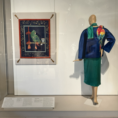 photo of a window display at MFA Boston featuring two works shown together: Japanese fukusa (gift cover) and Oscar de la Renta ensemble (jacket, dress, scarf)