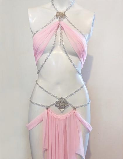 A photo of a wispy pink dress with delicate chains, displayed on a mannequin.